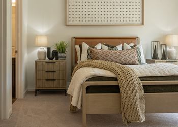 a bedroom with a bed and two nightstands with lamps and  at The Clearing at ONE28, Olathe, KS